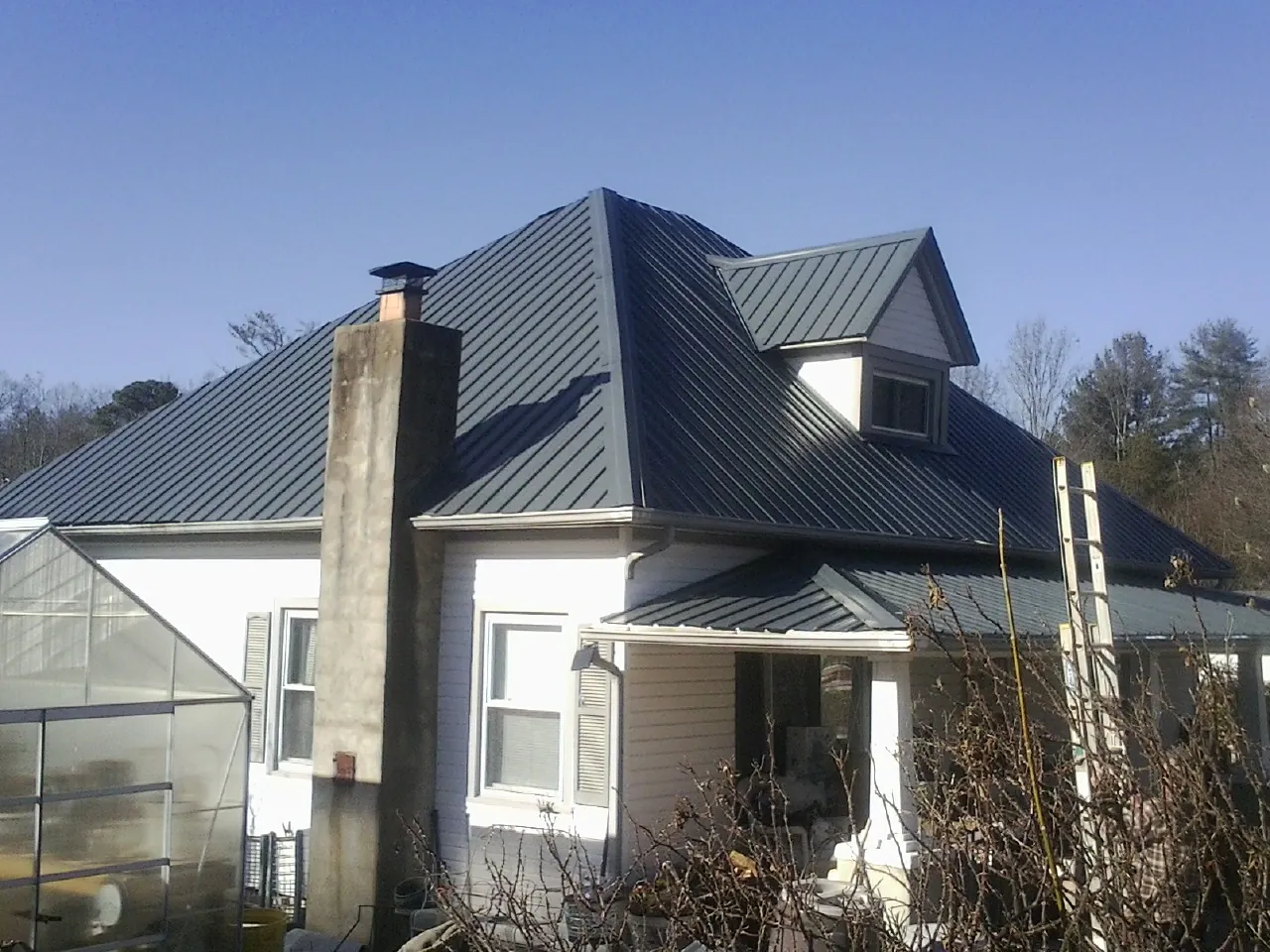 Dark blue standing seam metal roof on a white farmhouse with dormer — Slate & Tile Roof Repair by Roofing Brothers in Boxford