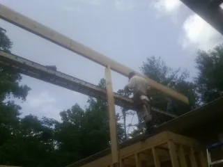 Carpenter setting a ridge beam over a new addition frame — Ice Dam Removal by Roofing Brothers in Boxford