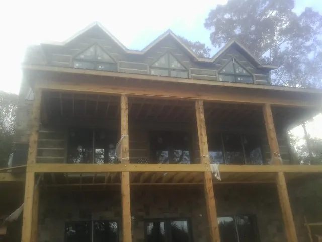 Dormers and porch framing on a large log home under construction — Roof Coating work by our crew in Boxford