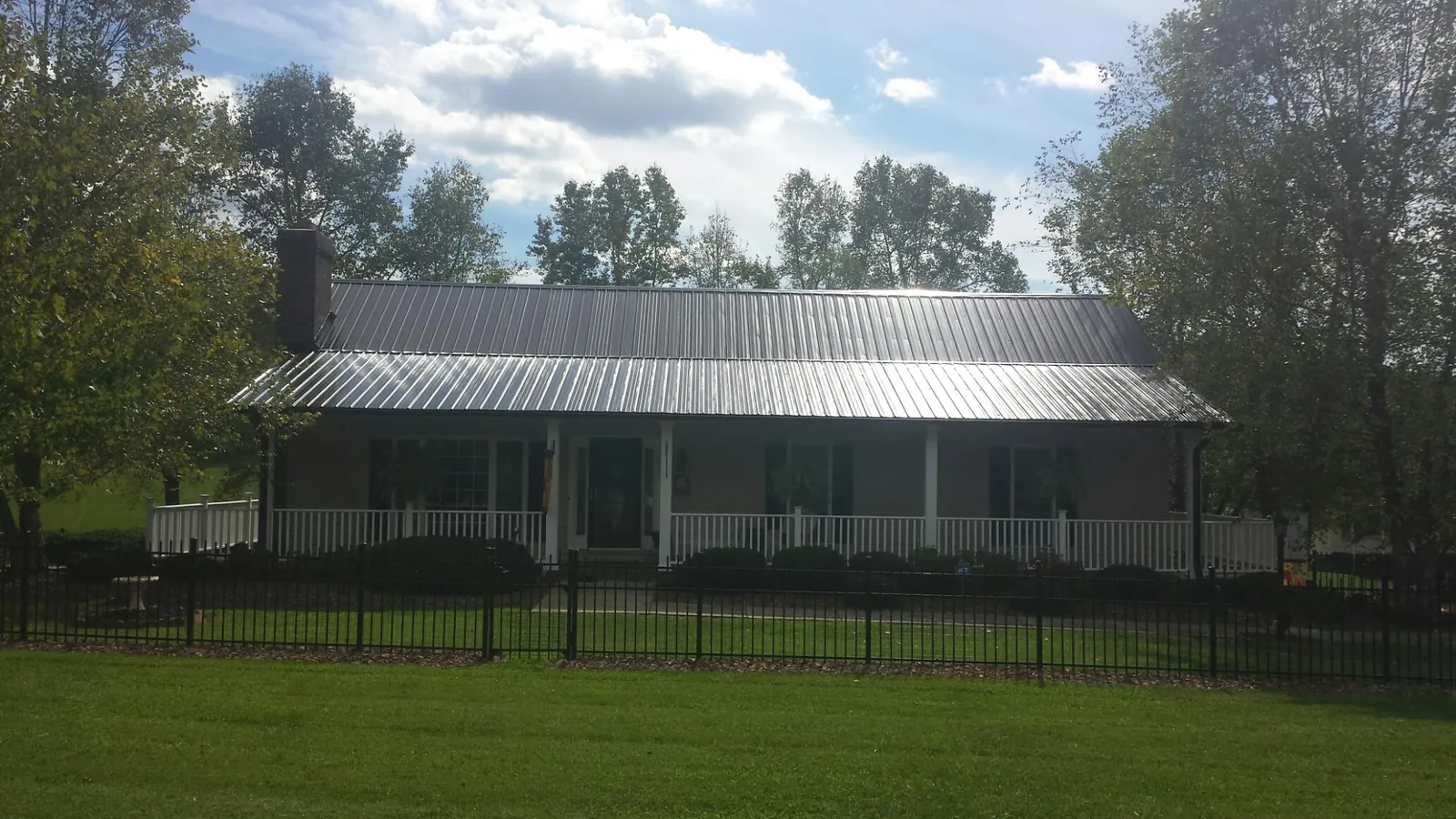 Gray metal roof on a brick ranch with a full width front porch — Gutter Guard Installation work by our crew in Boxford