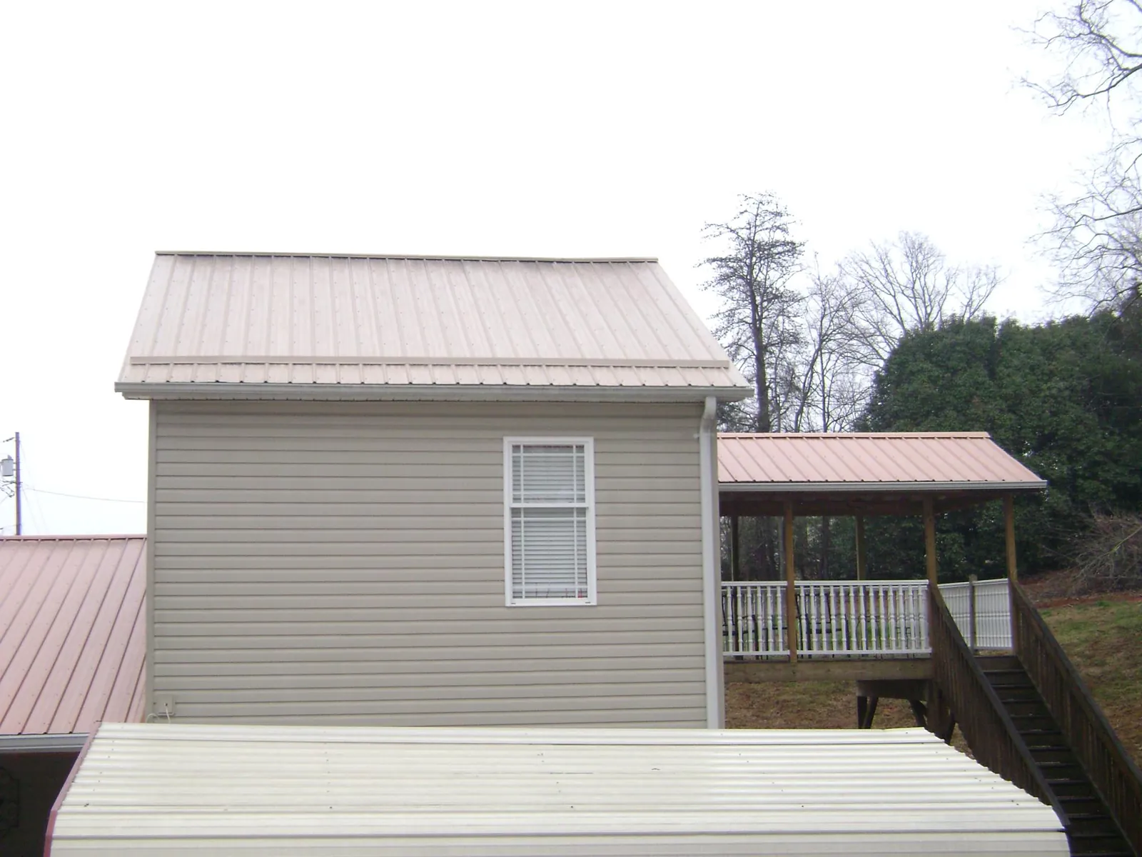 Tan metal roofs on a two story addition and attached porch, from a Roof Replacement job in Boxford