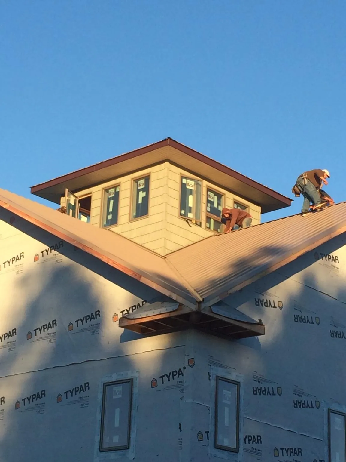 Roofers working around a rooftop cupola on a new metal roof at sunset — Roof Waterproofing in Boxford by Roofing Brothers